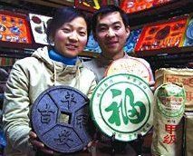 Yunnan couple displaying bricked pu cha (shu style) in tea shop.